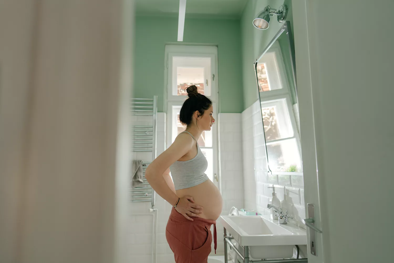 A person reflecting on their health routine in a bathroom, symbolizing the commitment to a daily medication schedule.