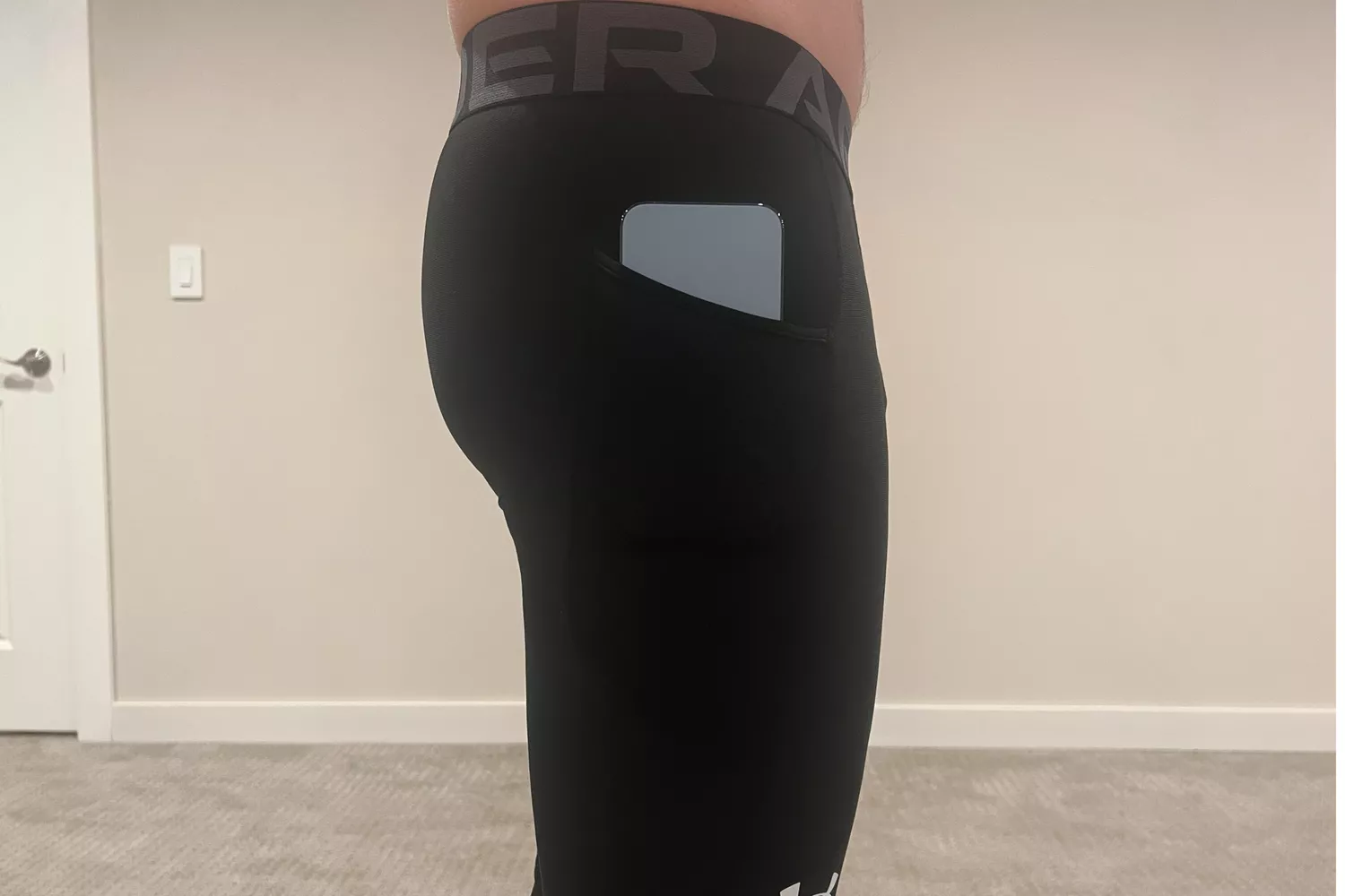 A runner with a smartphone securely tucked into the side pocket of black athletic leggings.