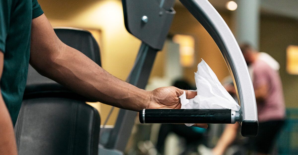 A clean fitness center floor with neatly arranged weight machines and sanitization stations.