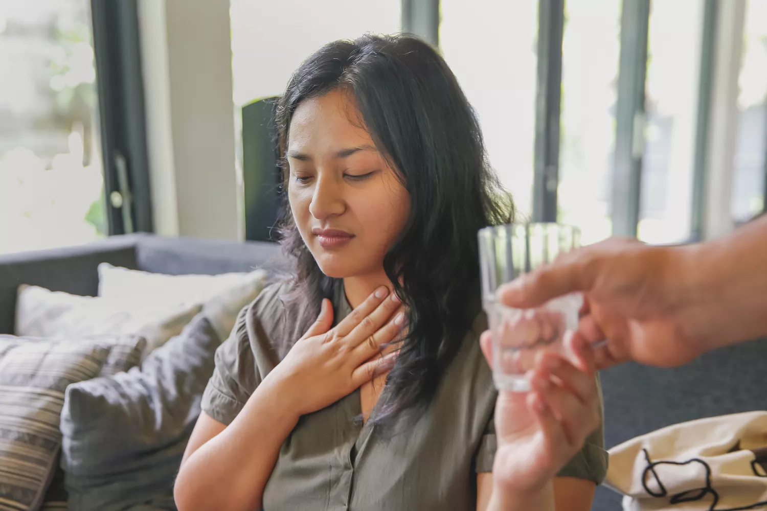 A person holding their throat, depicting the physical discomfort of nausea or digestive issues.
