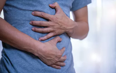 A man holding his stomach in discomfort, suggesting digestive issues.