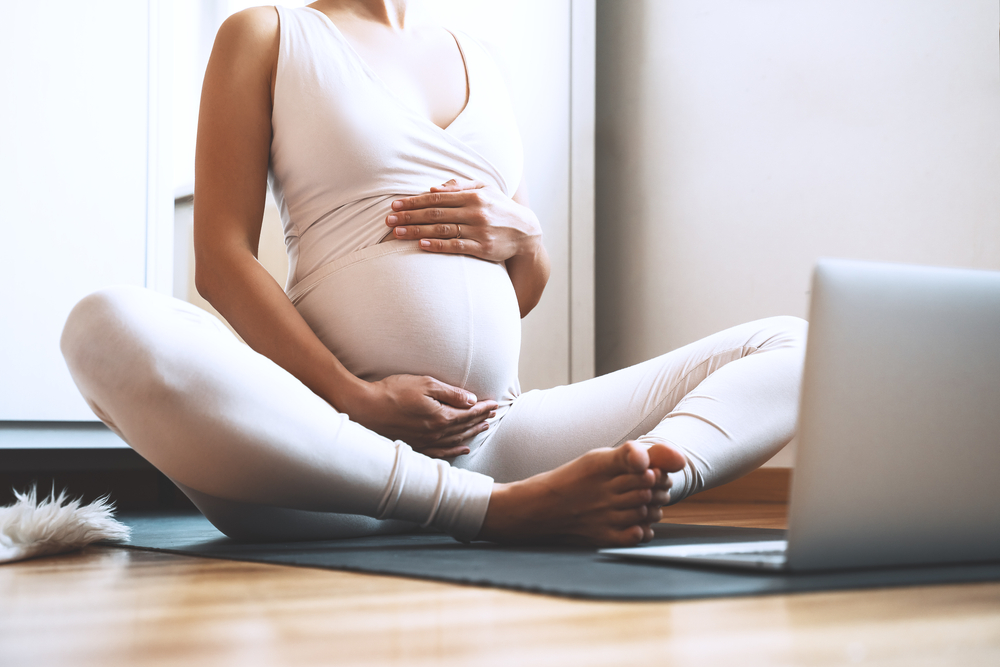 Pregnant woman performing low-impact aerobic movements in a fitness setting.