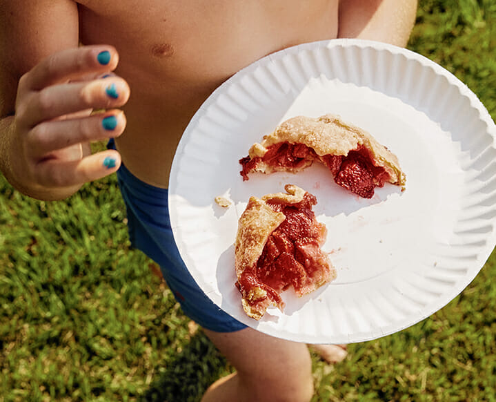 A step-by-step visual of shaping the dough around the strawberry filling.