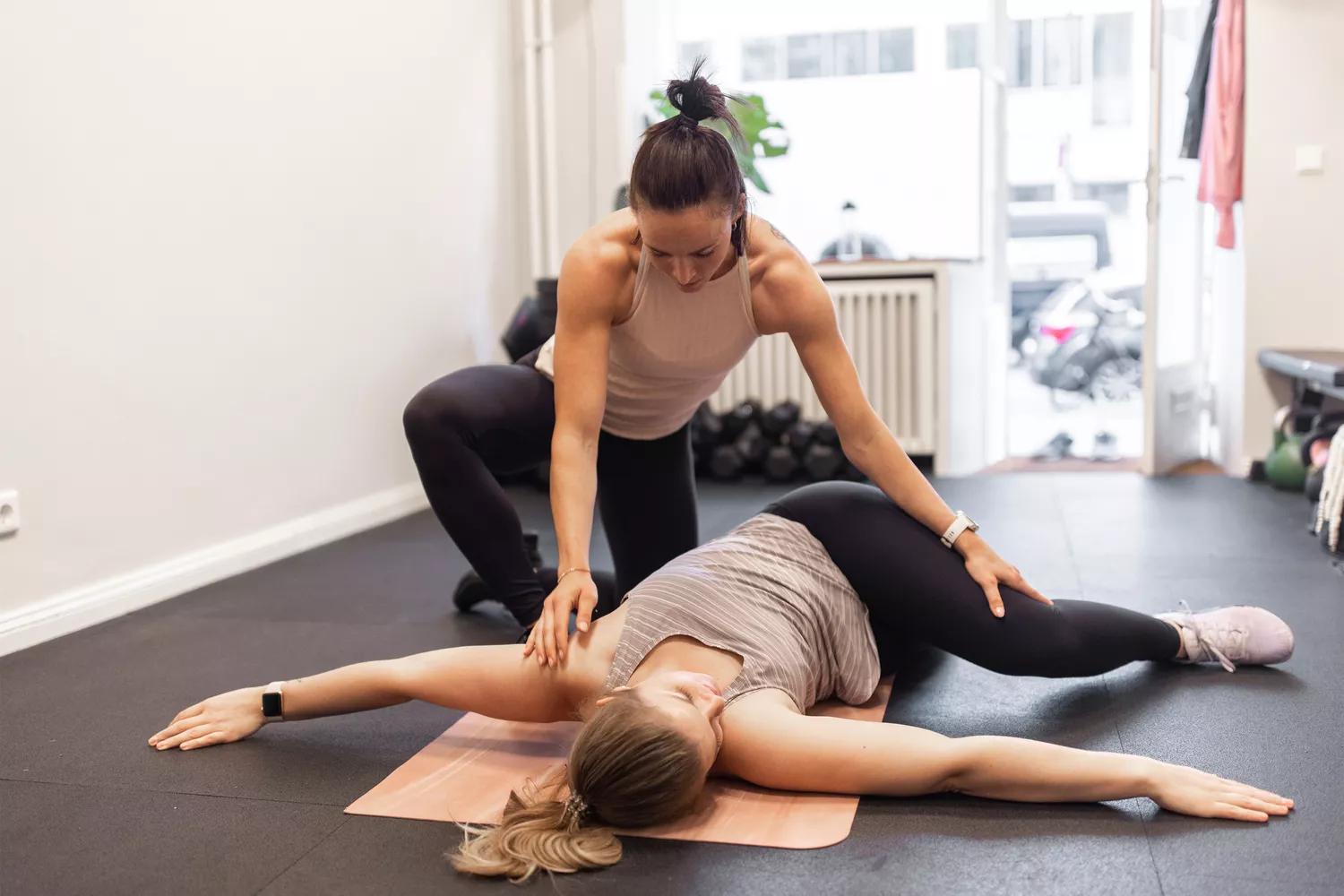 A professional yoga trainer assisting a woman during her stretching routine.