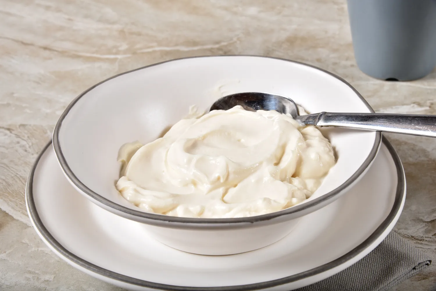 A white bowl containing thick, creamy white yogurt.