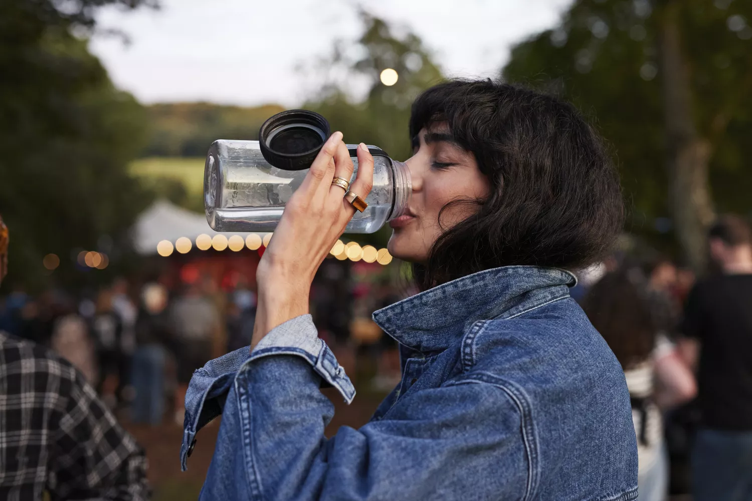 A person drinking from a water bottle to replenish fluids.
