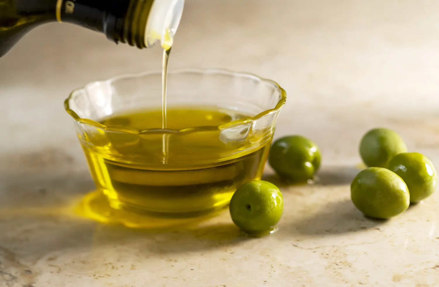 A glass bowl filled with clear yellow olive oil.