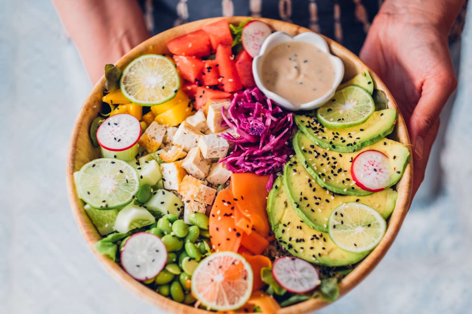 A colorful Buddha bowl with avocado, tofu, and fresh vegetables.