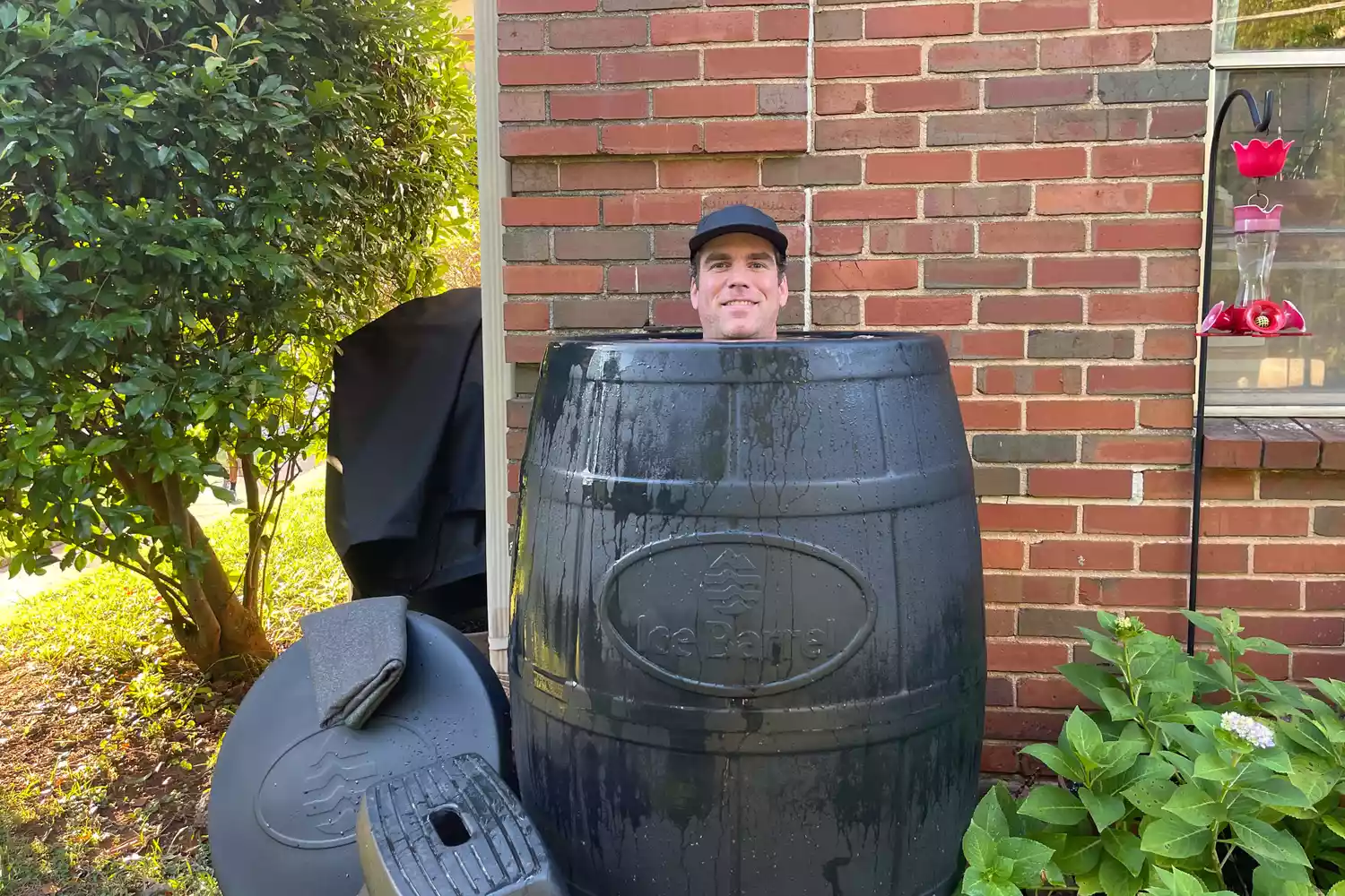 A man comfortably submerged up to his shoulders in a black Ice Barrel outdoors.