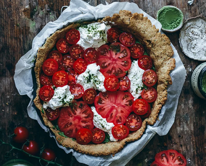 A close-up slice of tomato tart showing the layers of pesto, ricotta, and tomatoes.