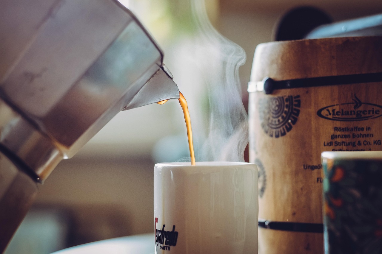 Thick white coconut cream being swirled into a dark mushroom coffee base