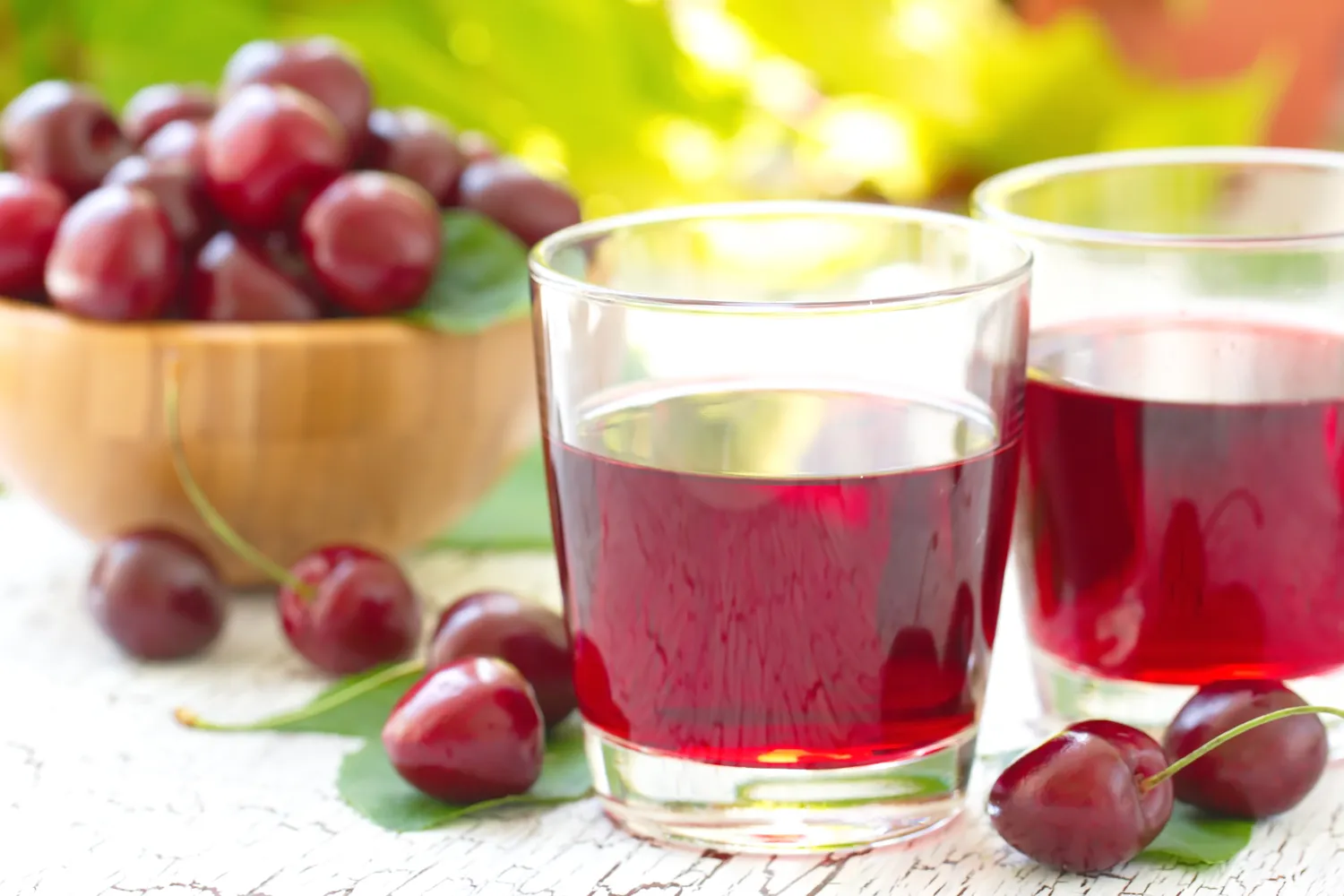 Tart cherry juice in a glass surrounded by fresh dark berries.