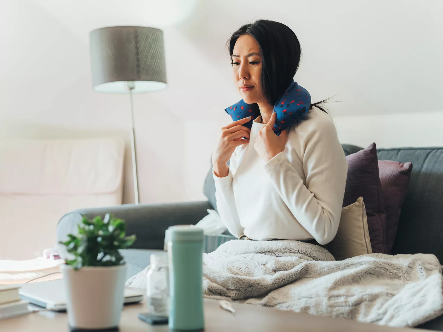 A woman using a heating pad on her arm to relieve injection site discomfort.