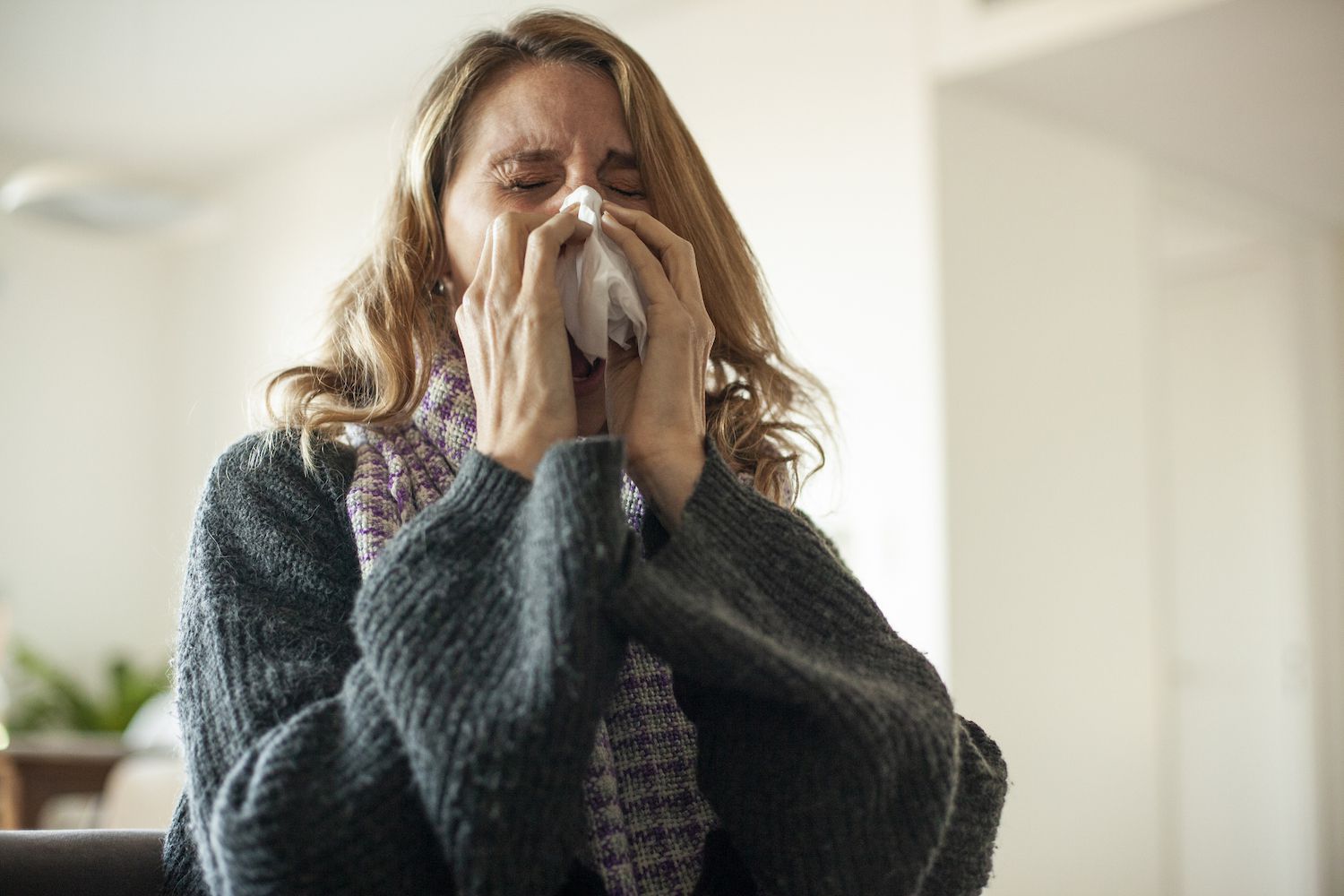 A woman managing symptoms of a cold at home, emphasizing the need for patient comfort during the recovery process.