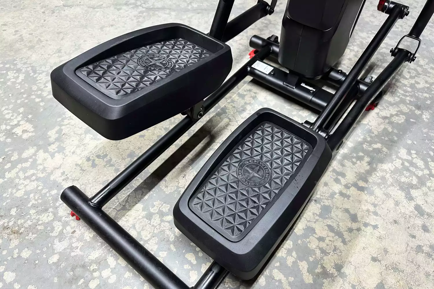 Close-up of the textured oversized foot pedals on a Schwinn elliptical machine.