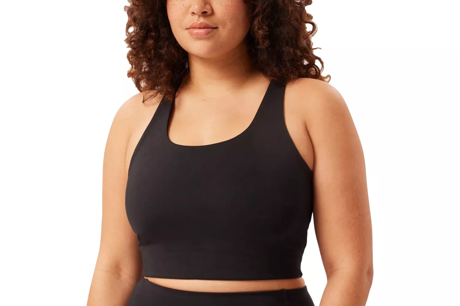 A woman modeling a black sports bra that shows a proper fit without spillage or strap digging.