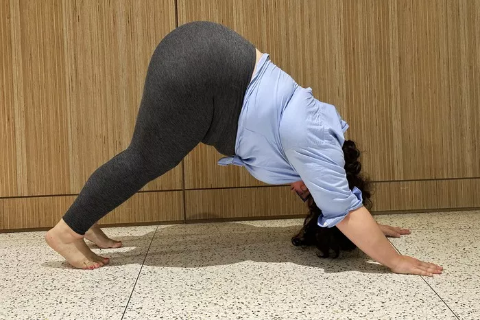 A person in gray leggings performing a downward dog yoga pose to show fabric stretch and fit.