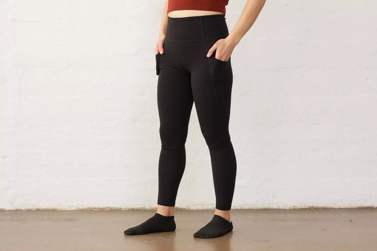 Side profile of a woman wearing black leggings with a visible side pocket for phone storage.