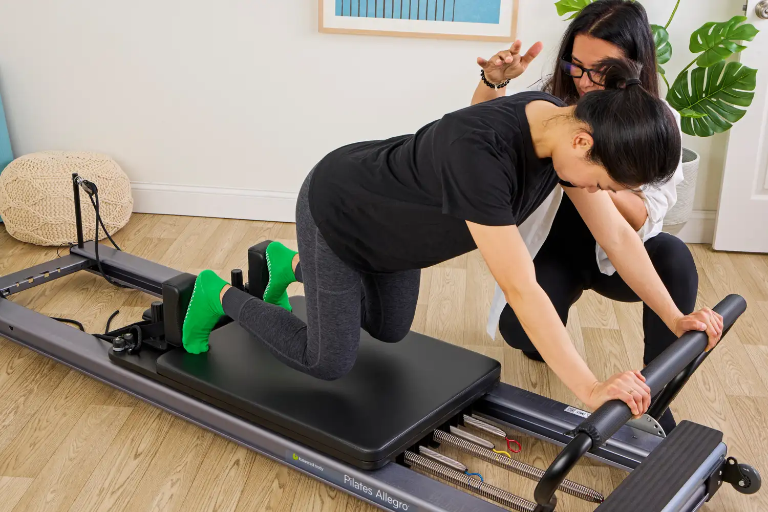 A person kneeling on a Balanced Body Allegro Reformer during a dynamic movement.