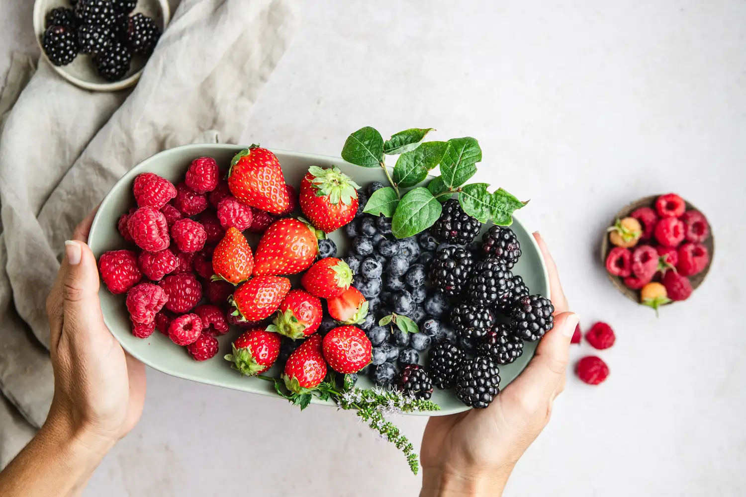 A bowl filled with fresh raspberries, strawberries, and blueberries.