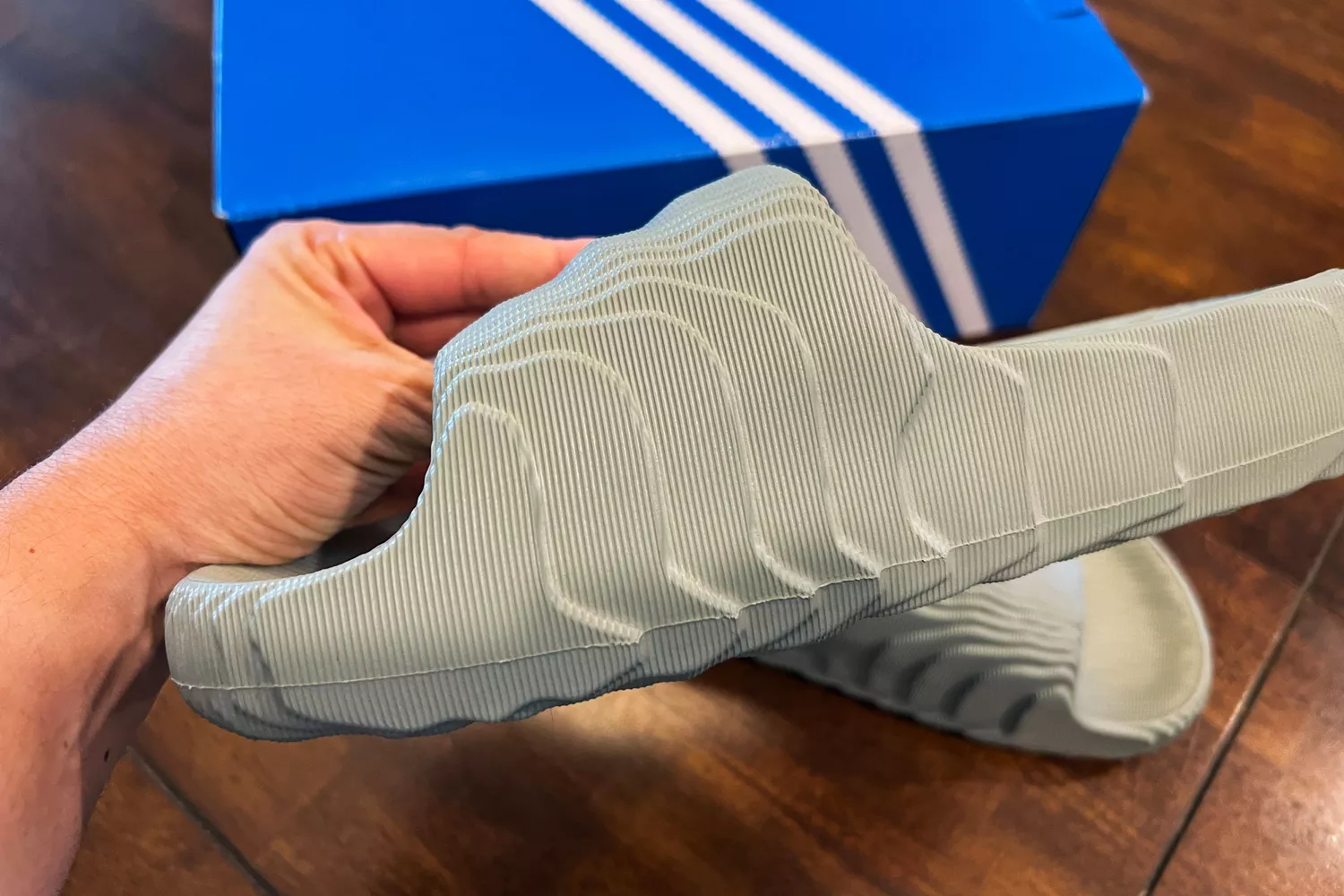 A hand holding an Adidas Adilette 22 slide showing its unique 3D-effect textured foam construction.
