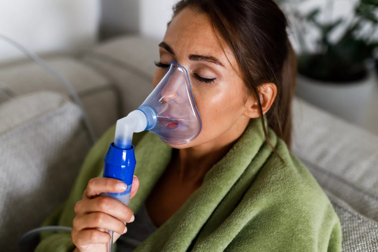 An individual using a nebulizer machine at home to inhale saline solution.