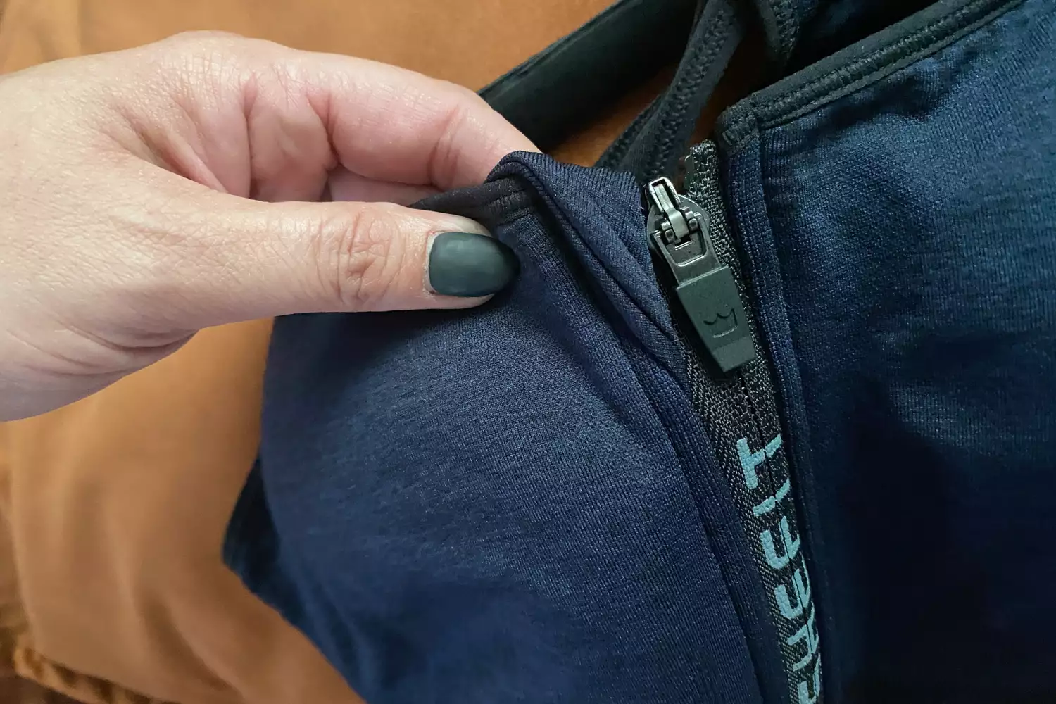 Close-up of a hand adjusting the front zipper on a high-performance SheFit sports bra.