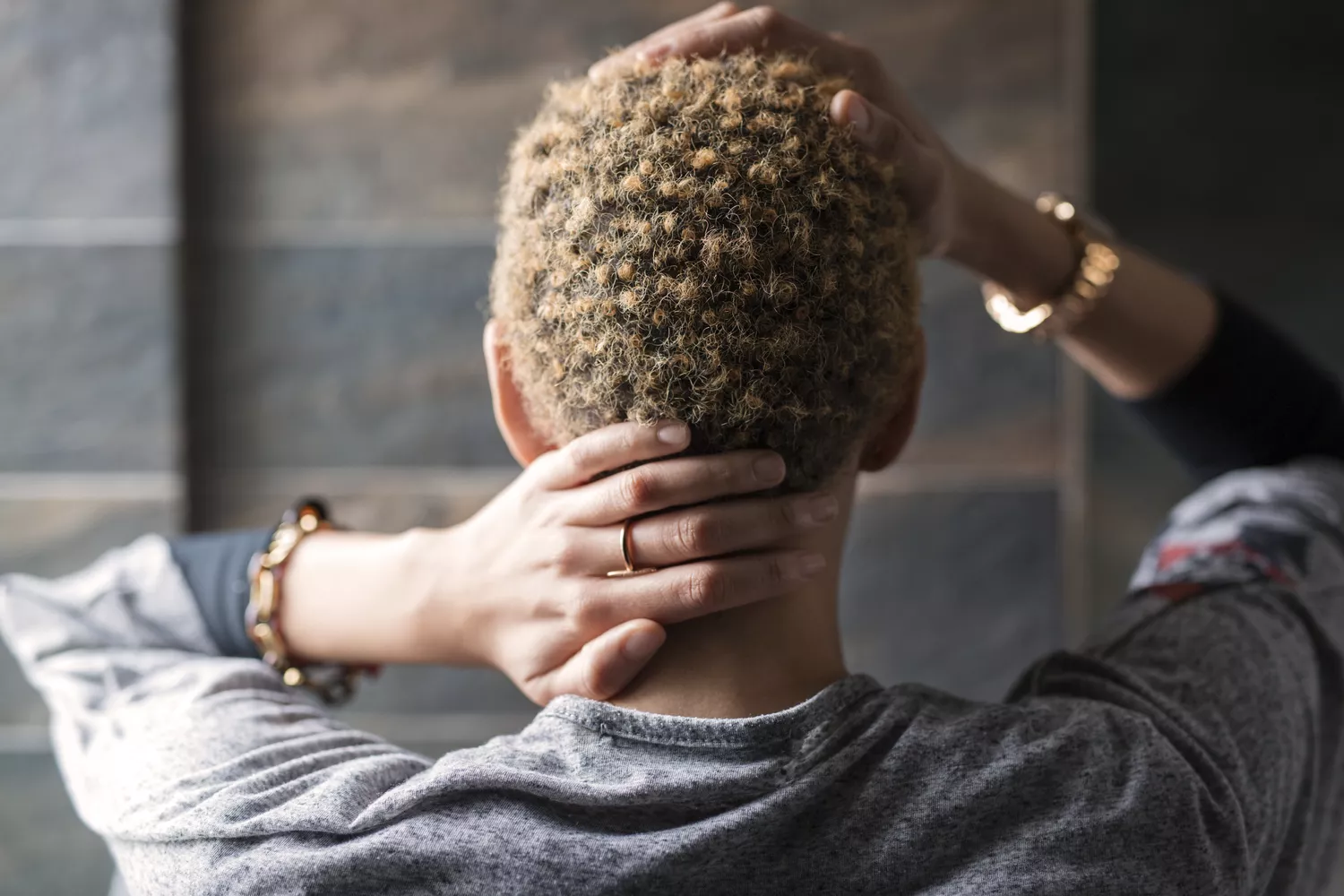 A person holding their neck and head in a gesture of pain and exhaustion.