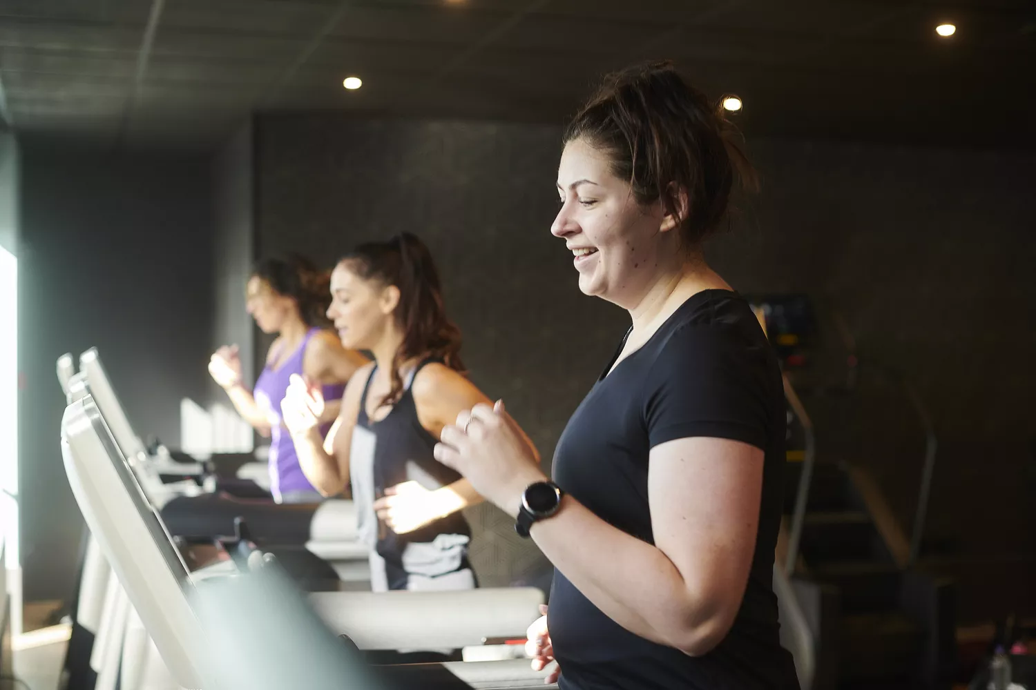 A group of women walking on treadmills in a gym, highlighting regular cardiovascular exercise.