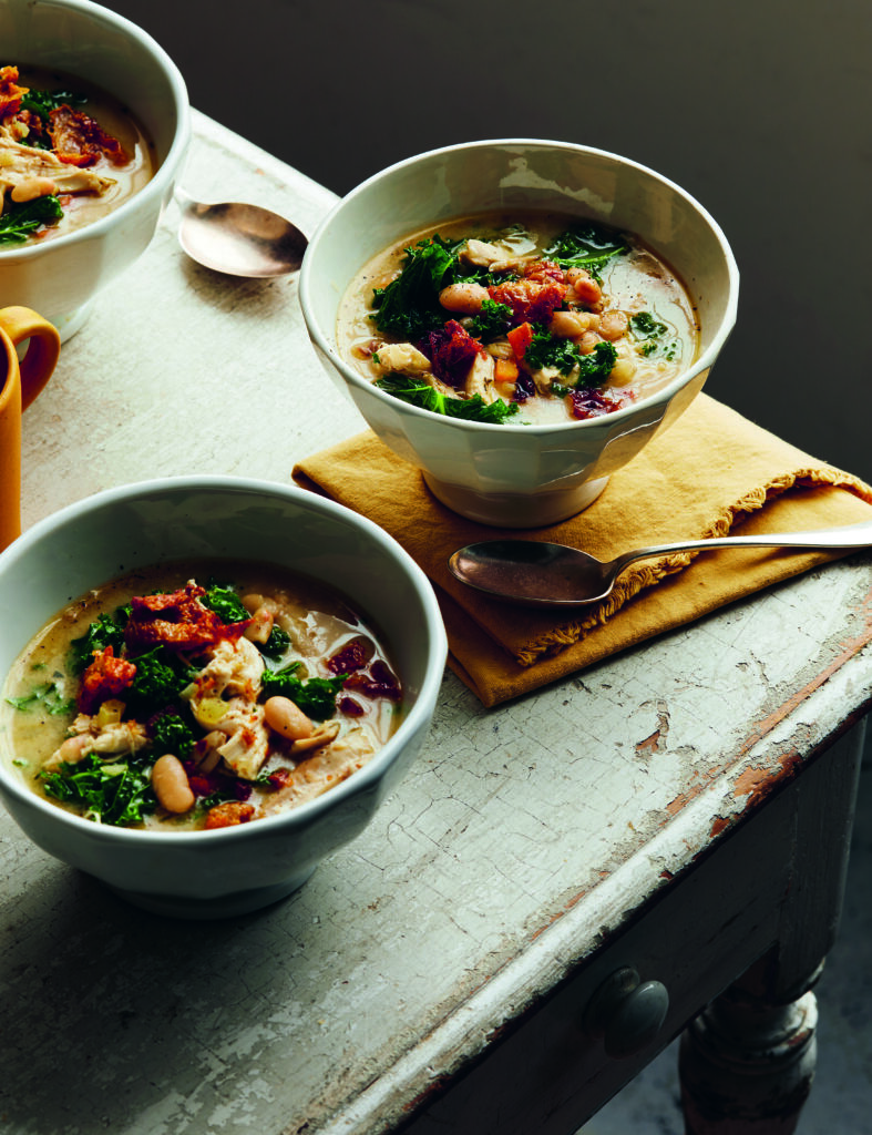 A vibrant plated 'Beanotto' dish garnished with fresh green herbs and a drizzle of olive oil.