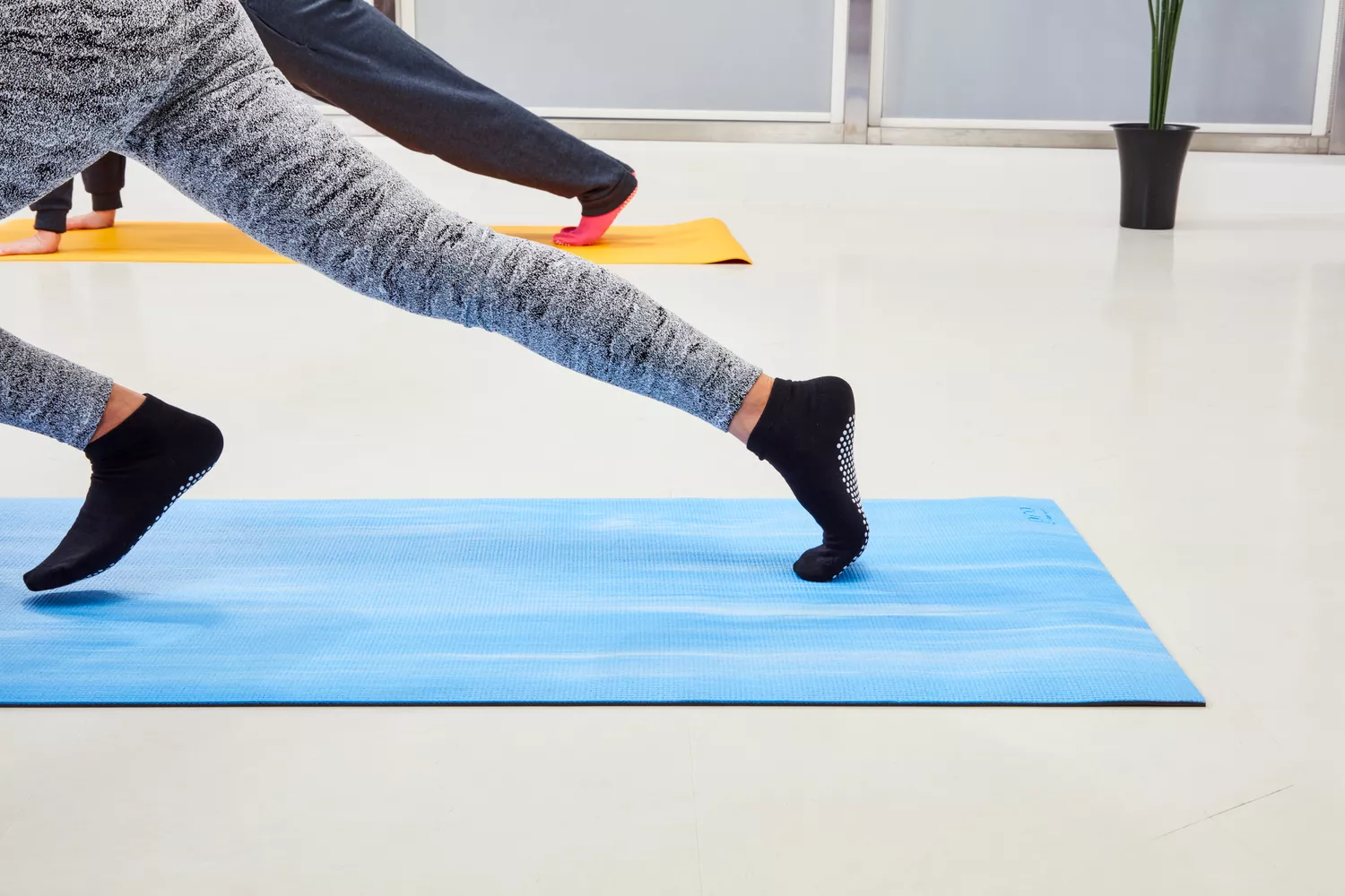 A person practicing a deep lunge on a high-grip yoga mat.