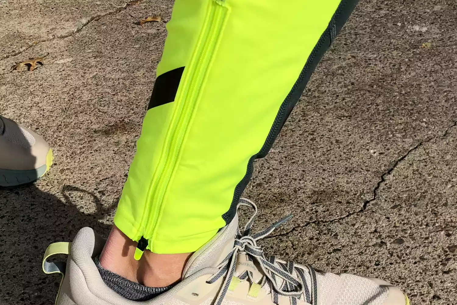 Close-up of neon yellow running tights and athletic shoes on a sidewalk.