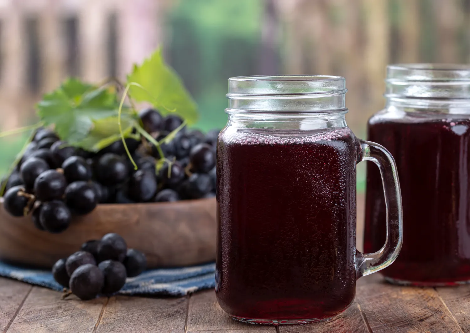 Two mason jars filled with deep purple grape juice.