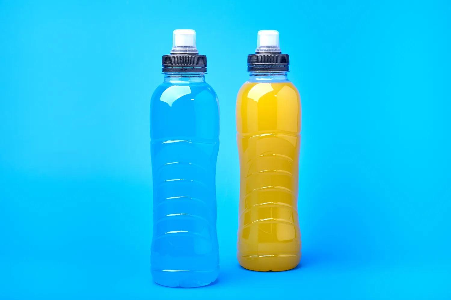 An array of various colored sports drinks in bottles.