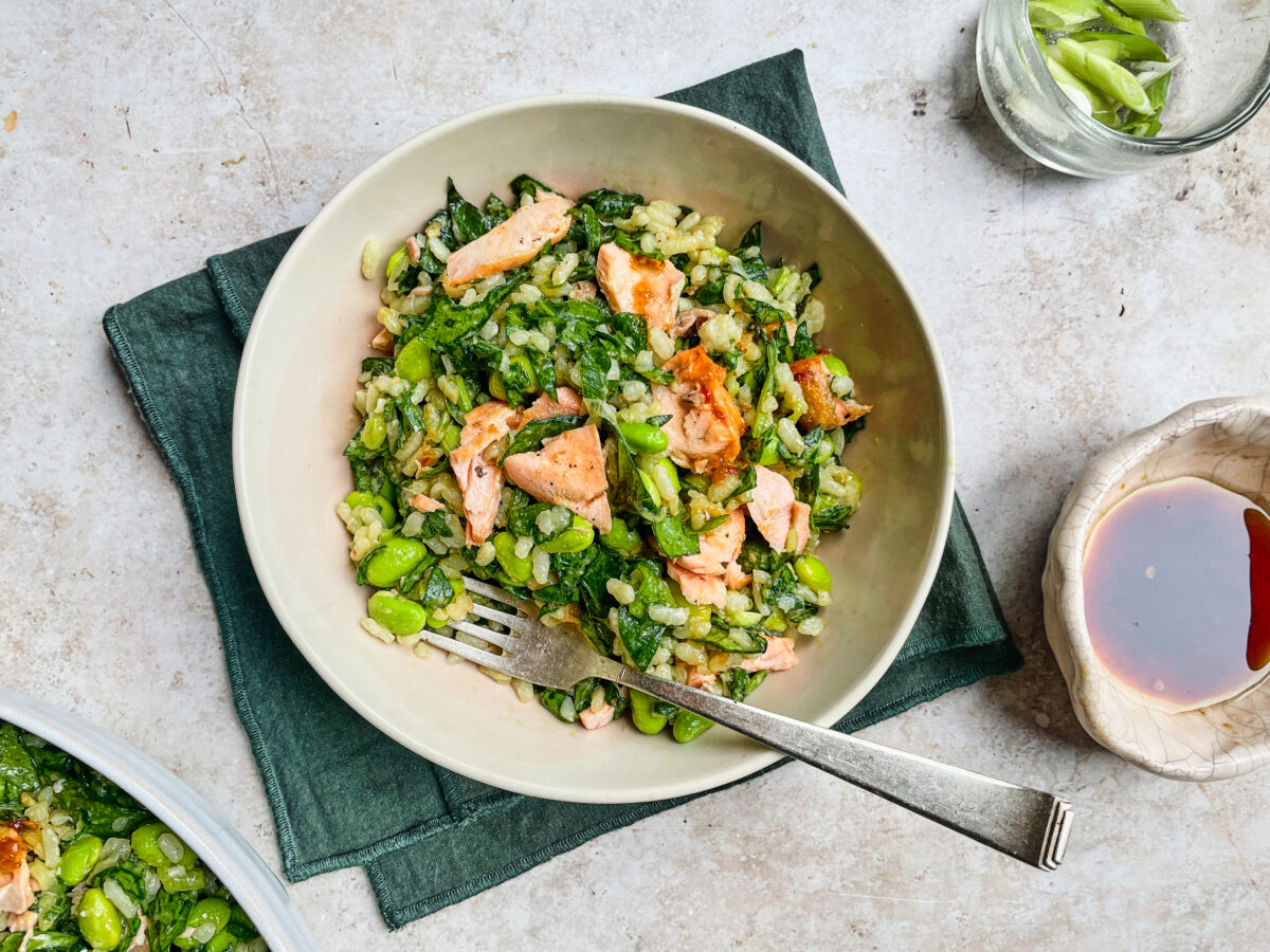 A top-down view of a Sweet Chilli Salmon Rice Salad featuring flaked salmon, edamame, and fresh greens.