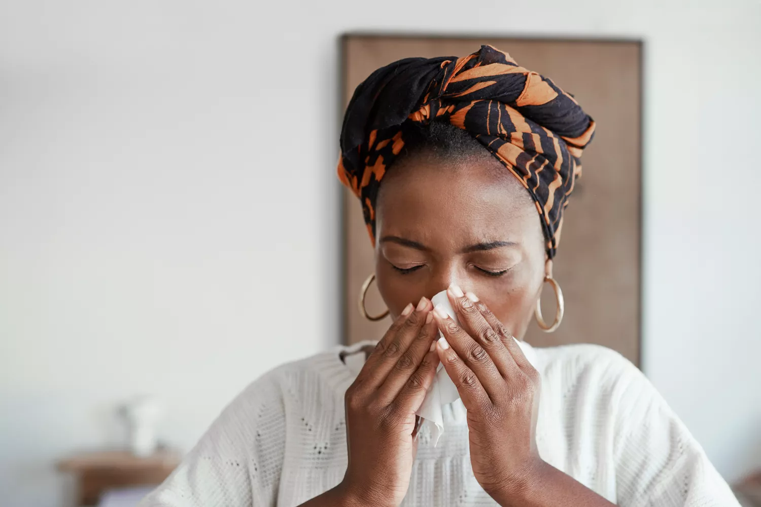 A person in bed using a tissue to blow their nose, illustrating a physical barrier to sleep.