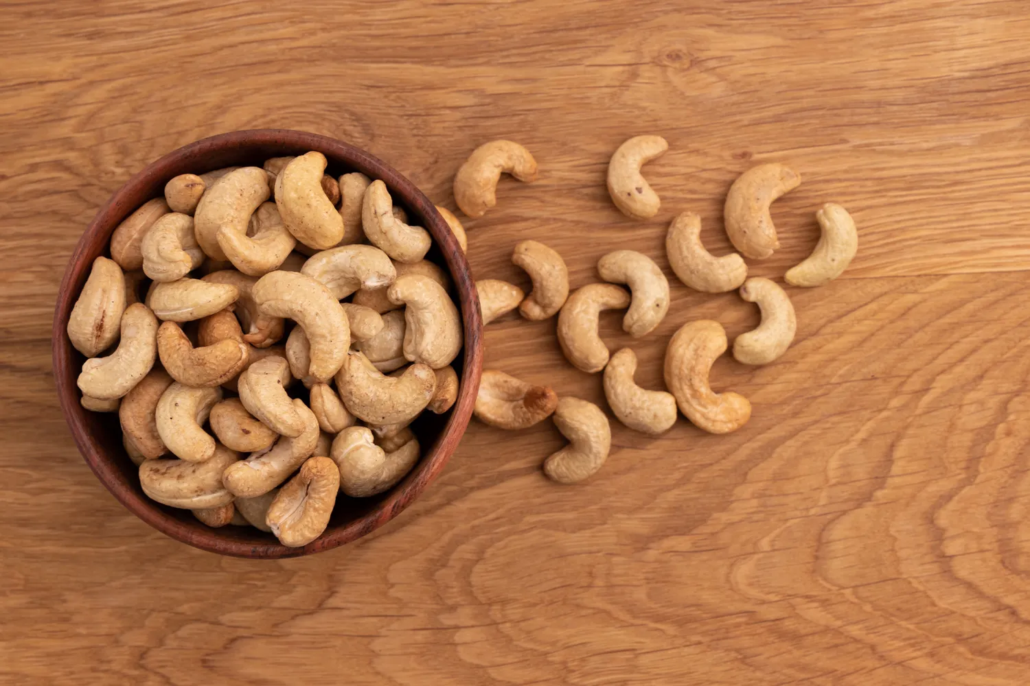 A handful of raw cashew nuts on a plain background.